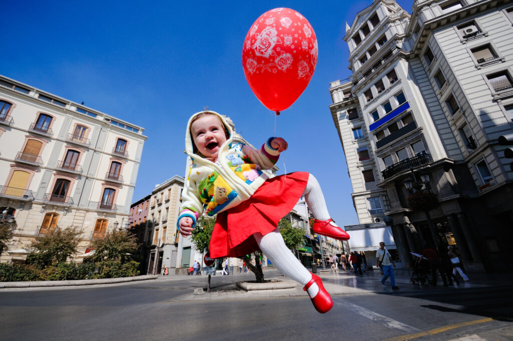 Bambina con palloncino che salta per le vie della città